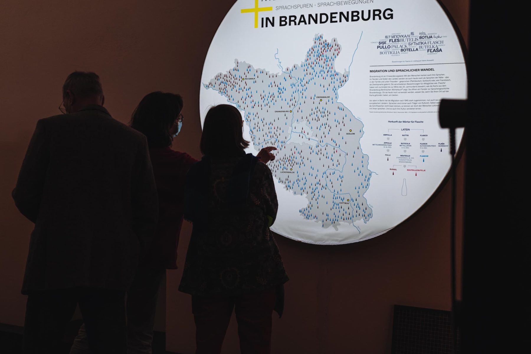 Drei Personen vor einem großen weißen Leuchtkreis mit Text