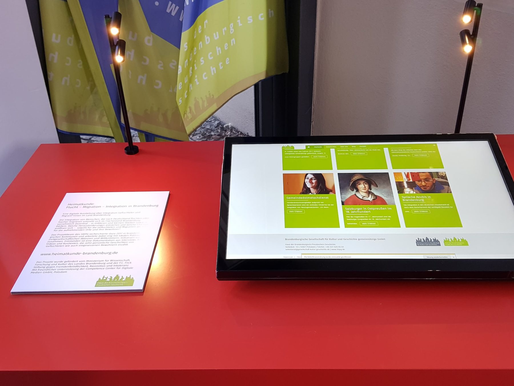 Ein roter Tisch mit einer Medienstation und einer Infotafel