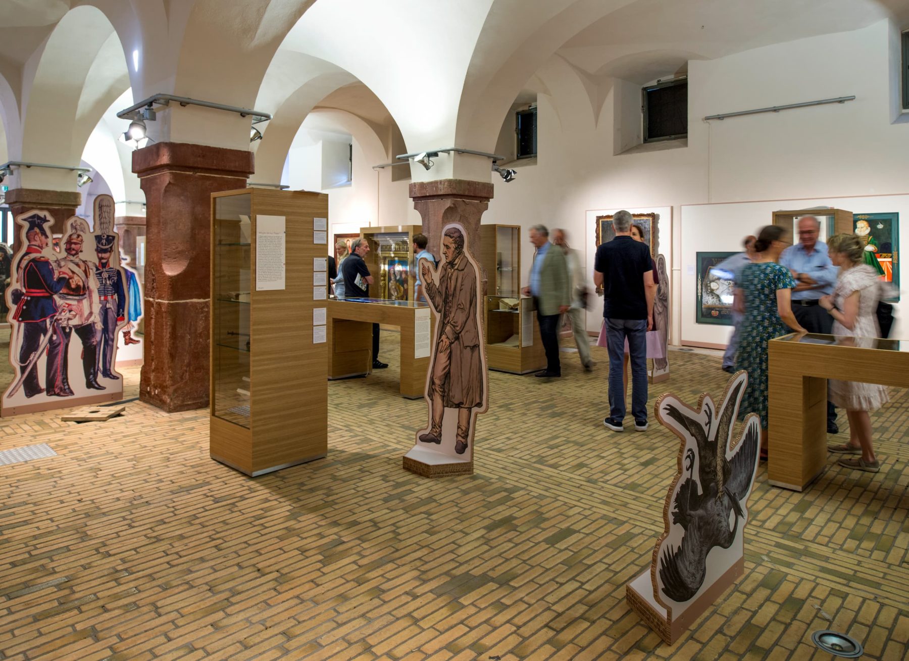 Eine Gewölbehalle mit Pappfiguren und Ausstellungsvitrinen