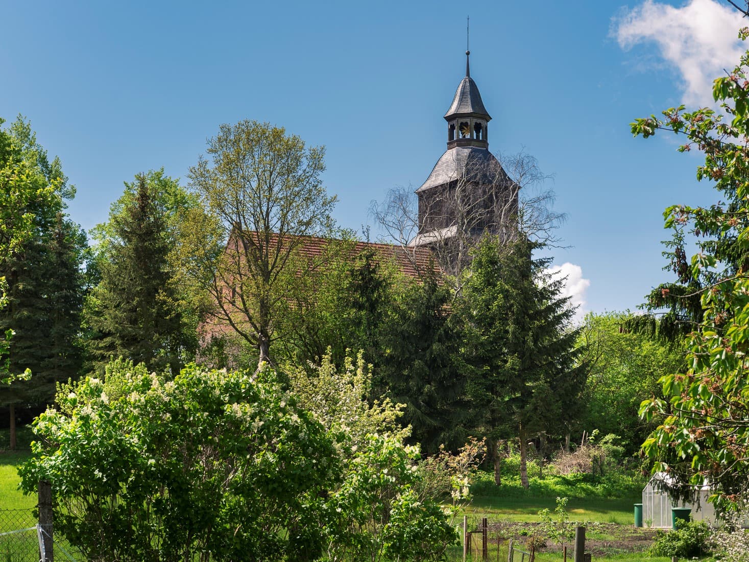 Kirche hinter grünen Büschen und Streuchern