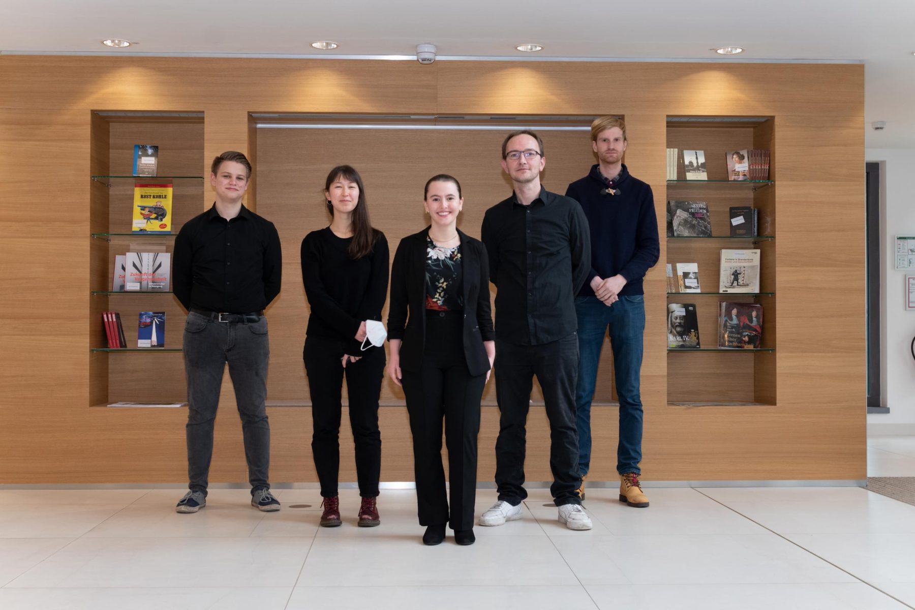 Fünf Personen in dunkler Kleidung in einem Museumsfoyer