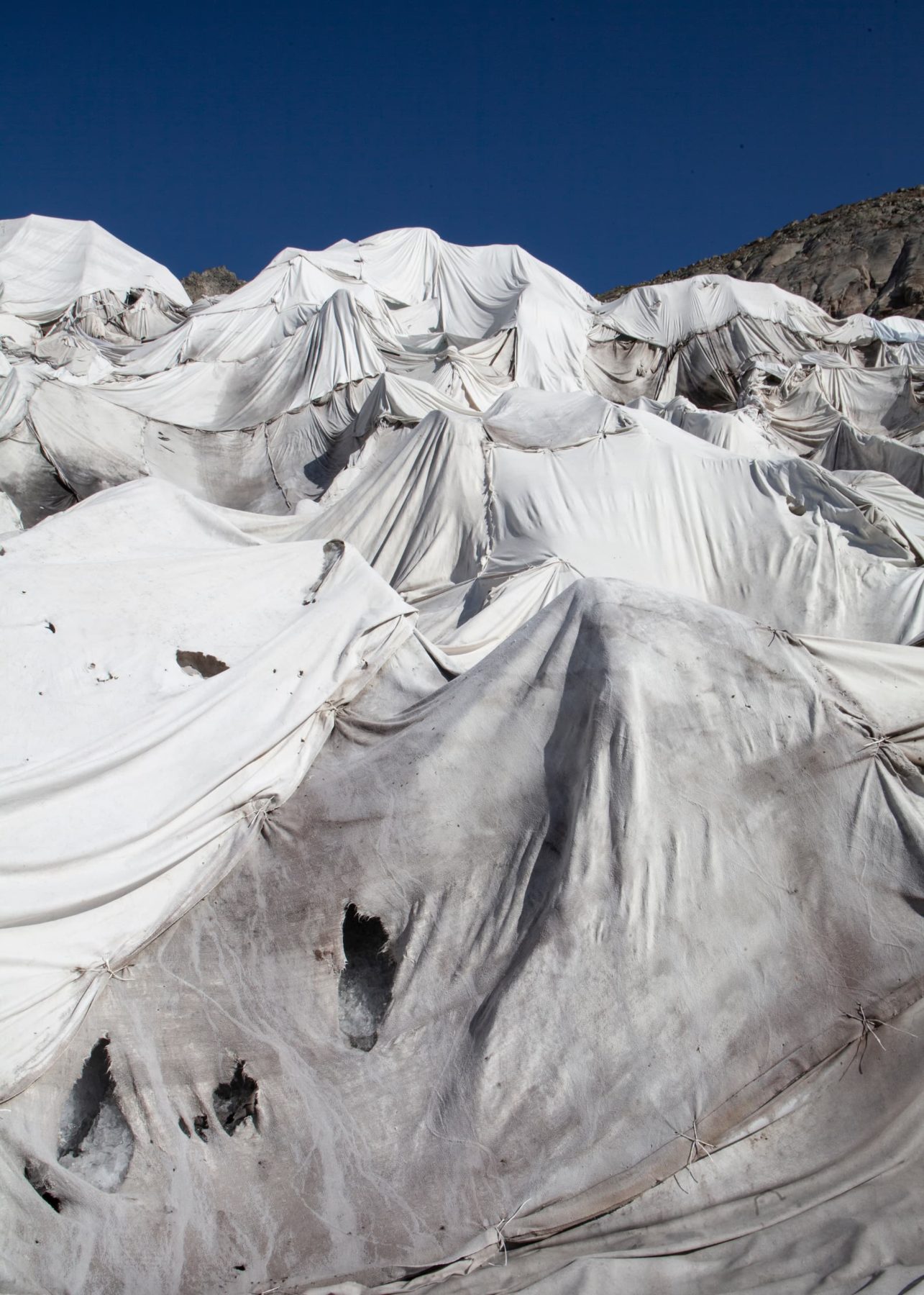 Ein Gletscher bedeckt mit weißen Tüchern vor blauem Himmel