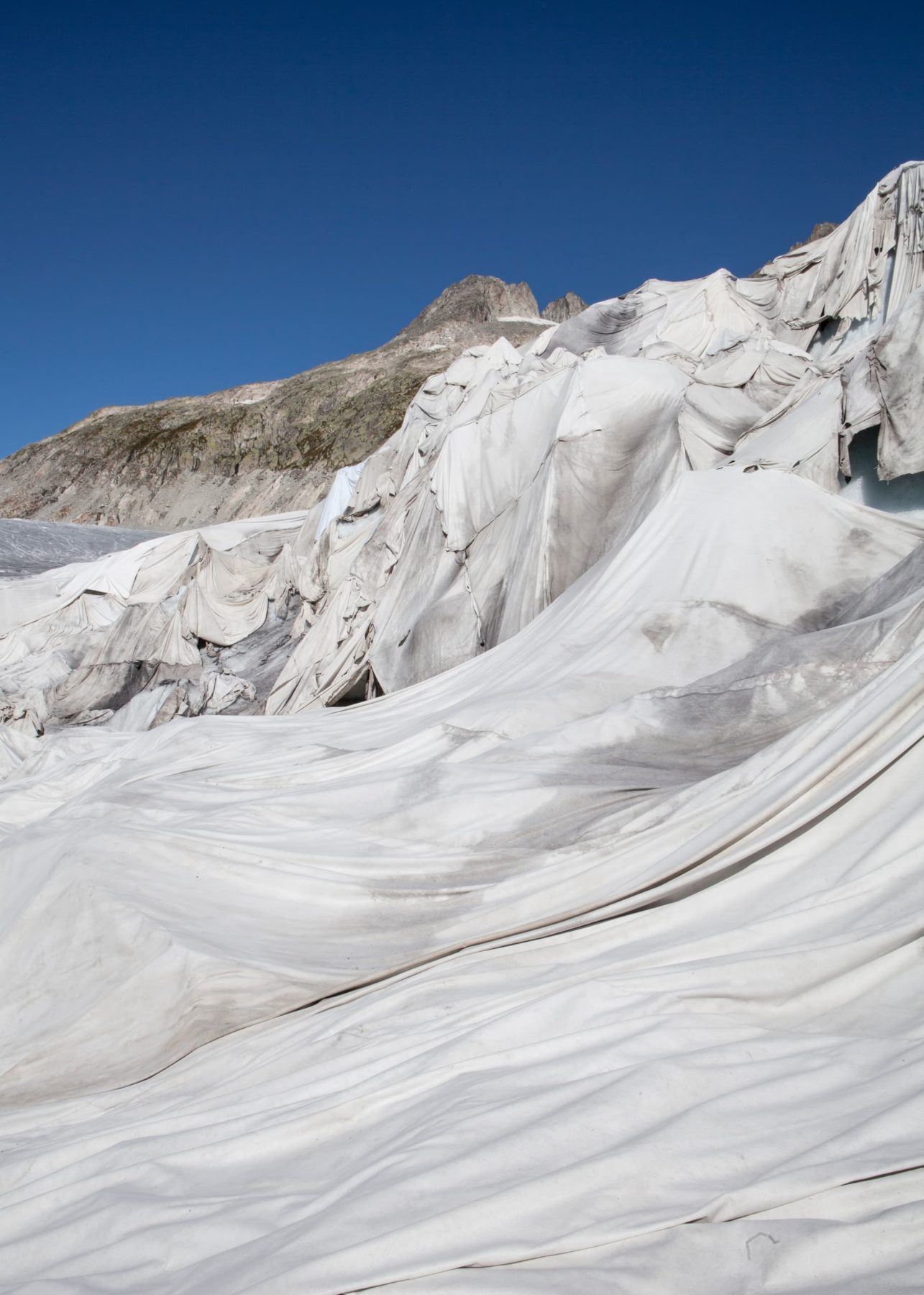 Ein Gletscher bedeckt mit weißen Tüchern vor blauem Himmel