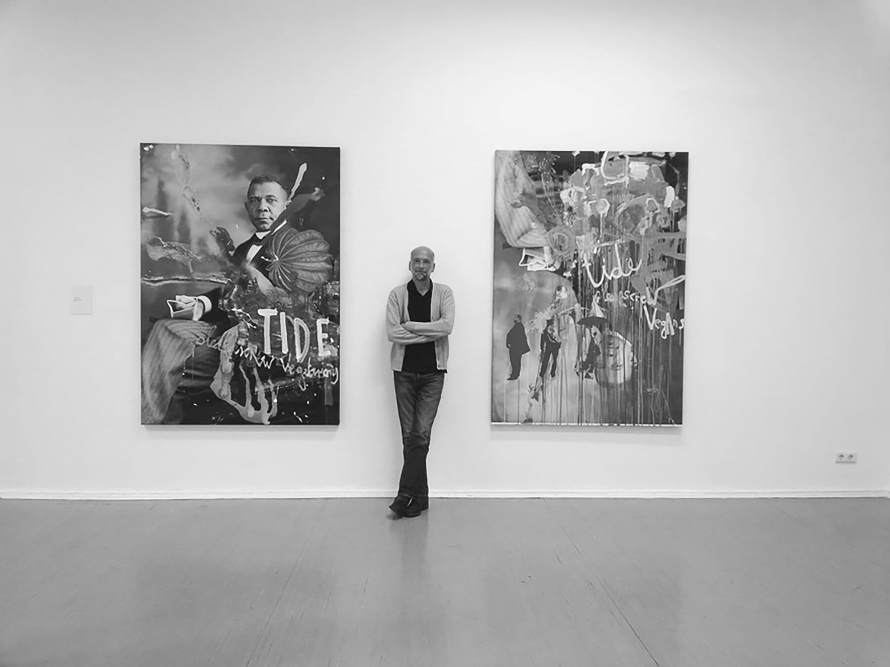 Eine Person steht zwischen zwei mannshohen Gemälden, die an einer Wand hängen.