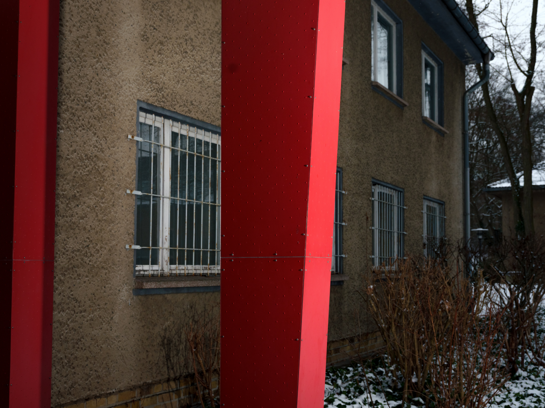 Die Außenansicht eines Gebäudes. Davor eine rote Säule.