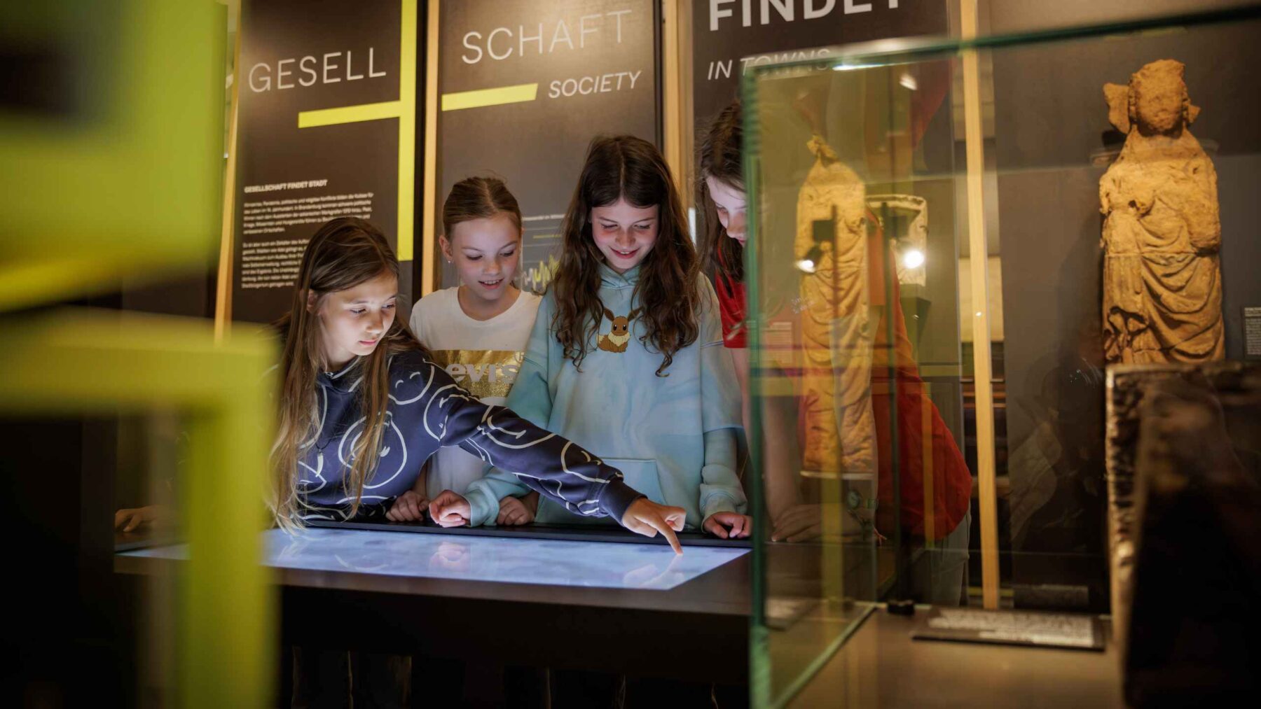 Drei Schülerinnen schauen sich eine Medienstation in der Brandenburg.Ausstellung an